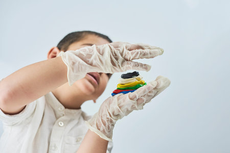 Close-up portrait of mixed raced child in glasses and gloves experimenting with slime