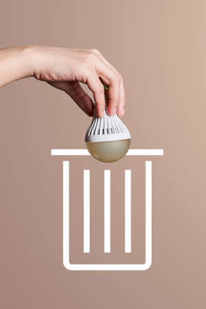 A person throwing light bulb for recycling. Hand throws used light bulb into garbage. Concept of sorting, recyclingの写真素材