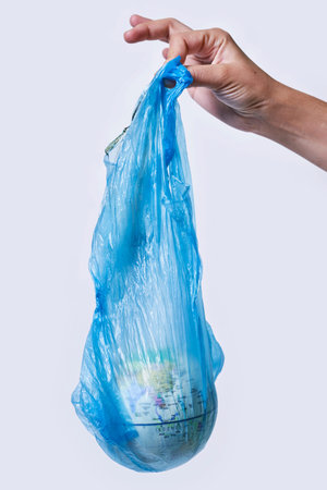 Global Warming and Climate Change concepts. Woman hand holds a glove in plastic bag. Environmental...