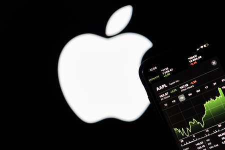 Tashkent, Uzbekistan - 29 October, 2021: A person holding smartphone with Apple company shares current stock market price charts and graphs over Appleのeditorial素材