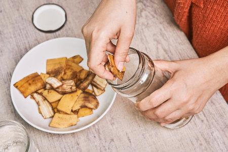A person making banana peel fertilizer with banana cuts. Putting small pieces of banana skin into...