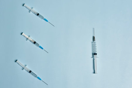 Syringes on bright blue background. Symbol of three  booster shot. Booster vaccine dose injection