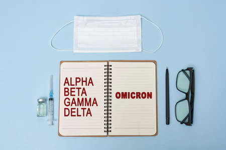 New omicron variant of Covid-19 text on notepad. Workspace or working desktop of doctor, frontliner fighting against covid. New South African variant of coronavirus, with increased reinfection riskの写真素材