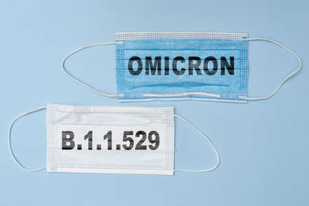 Female doctor holds a face mask with - Omicron variant text on it. Covid-19 new variant - Omicron. Omicron variant of coronavirus. SARS-CoV-2 variant of concernの写真素材