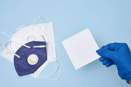 Doctor hand holds a white card over a pile of face masks. Copy spaceの写真素材