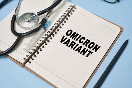 New omicron variant of Covid-19 text on notepad. Workspace or working desktop of doctor, frontliner fighting against covid. New South African variant of coronavirus, with increased reinfection riskの写真素材