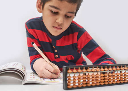 Schoolboy do mental math. Mental mathematics. 8 years old multiracial boy busy with mental arithmetic. Boy in math courses. Doing homework, math at home. Boy works on the accounts of mental arithmeticの写真素材