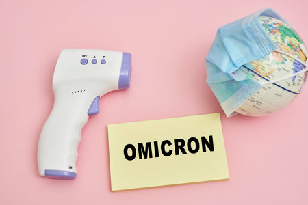 Miniature world globe with face mask and infrared thermometer. New virus Omicron variant. omicron...