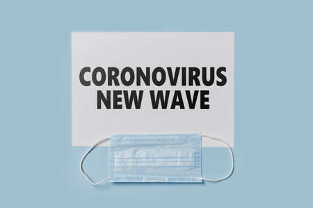 Coronavirus new wave text on paper and face mask. Lockdown, quarantine due to new Covid-19 variantの写真素材