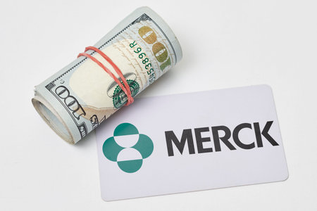 Tashkent, Uzbekistan - 22 November, 2021: Pile of us dollars and Merck card. Merck - multinational...