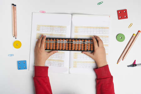 Doing mental math or mental arithmetic. Hand of little boy using abacus for calculating. Learning to use abacus on mental math courses. A kid doing math at home with abacusの写真素材
