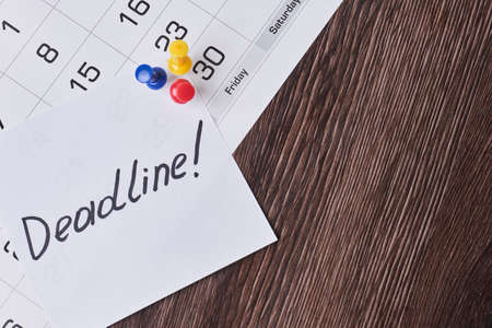 Deadline concept. A paper with Deadline text pinned on monthly calendar. White card with Deadline text pinned with push pins on calendar date. Last day, Last chance conceptsの写真素材