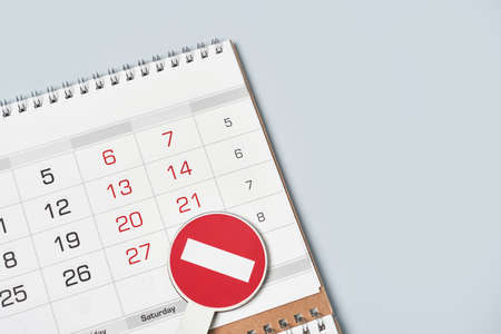Close-up view of monthly calendar and No entry traffic sign. Symbol of cancellation, forbidding and banning. Symbol of quarantine or lockdown. Banned vacation, quarantine restrictionsの写真素材