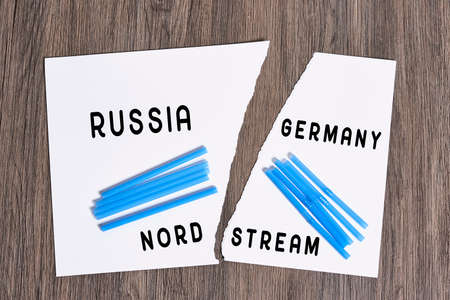 Plastic straws on Russian and German national flags. Nord Stream gas pipeline, sanctions and politics. Russia Vs Germany. Torn paper.の写真素材