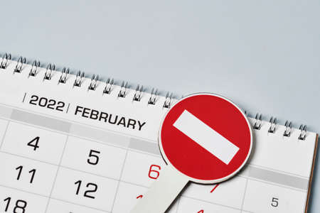 Close-up view of monthly calendar and No entry traffic sign. Symbol of cancellation, forbidding and banning. Symbol of quarantine or lockdown. Banned vacation, quarantine restrictionsの写真素材