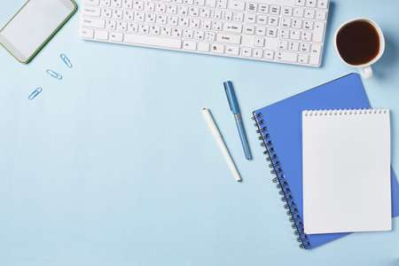 Bright office workspace. Work space with notepad, keyboard, coffee and glasses. Work space table...