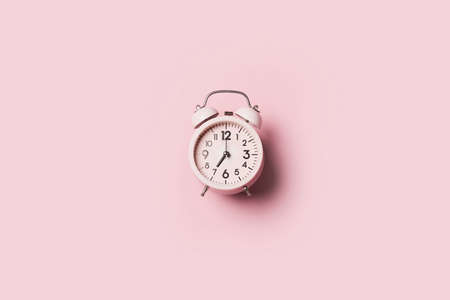 Pink alarm clock with hard shadow on pink background. Top view. Wake up alert concept. Morning routine.の写真素材