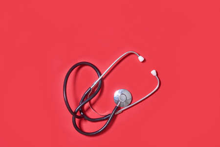 Stethoscope on red background. Theme of health care, medical treatment and disease prevention.の写真素材
