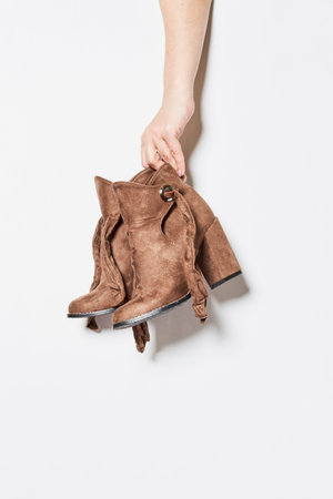Woman holding autumn beige leather suede boots Stylish womens shoes made from natural materials on white backgroundの写真素材
