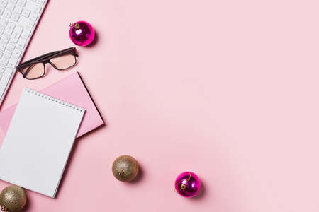 Home office table with Christmas decorations, coffee cup and notebook on pink backgraund. Flat lay, top view. Christmas workspace. Minimalismの写真素材