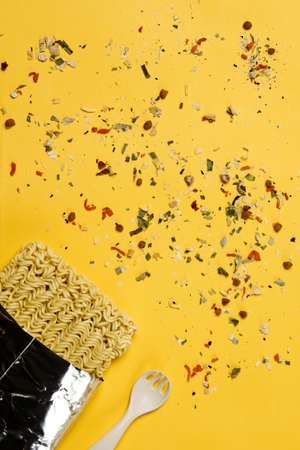 Instant noodles composition. Noodles and fresh vegetables and spices on yellow backgroundの写真素材