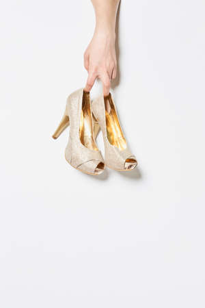 woman holding high heeled shoes front of an abstract backgroundの写真素材