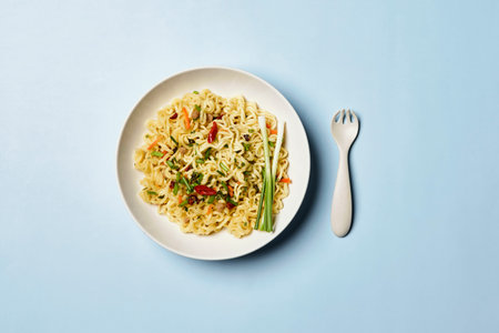 Instant noodles composition. Noodles and fresh vegetables and spices on bright blue backgroundの写真素材