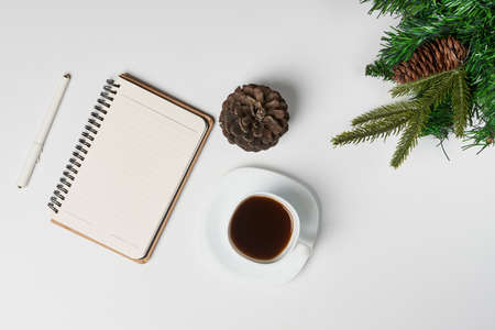 Christmas home office desk with notebook, cup of coffee and christmas decorations on white backgraund. Christmas card background notebook template. Top view with space for text.の写真素材