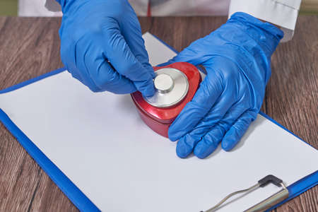 Doctor hands holding heart, donation and implantation, medic saving life on notebook. Notebook for recording the results of a patient examination.の写真素材