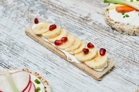 Crispbreads with cream cheese and fruits on white wooden backgraundの写真素材