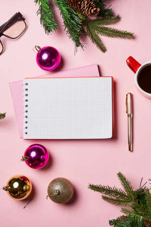 Christmas pink background with blank notebook, pen, christmas decorations and cup coffee. Christmas, New year planning, goals, to-do list or wish list concept. Copy space.の写真素材