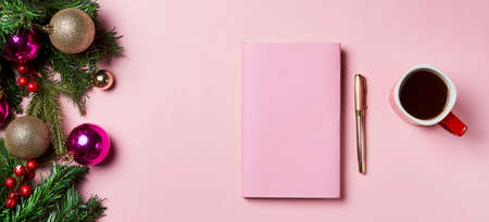 Top view photo of notebook pen keyboard cup of hot drinking gold christmas tree balls. Workspace with Christmas decorations and fir tree branches on pink background.の写真素材