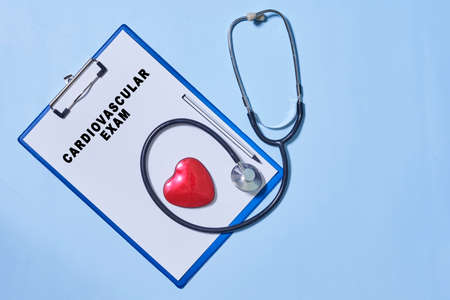 On blue background, phonoscope, pen and notebook for recording the results of a patient examination. Text Cardiovascular exam on notebookの写真素材