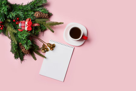 Christmas background with peper surrounded by Christmas decorations and a cup of coffee on pink backgraund. Letter to Santa or Christmas shopping listの写真素材