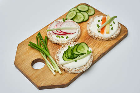 Rice cake with cream cheese and vegetables on wooden boardの写真素材