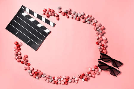 Movie clapper, pop corn and 3d glasses in a pink background. Flat lay. Cinema party concept.の写真素材