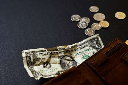 A single one-dollar bill in a mens leather wallet presents inflation, a currency war concept, global economic crisis situation. Shallow depth of field.の写真素材