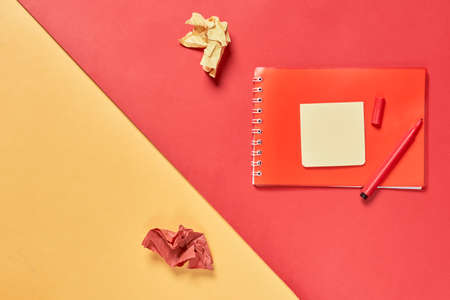 Red notebook with red pen and paper on colour background. Copy spaceの写真素材