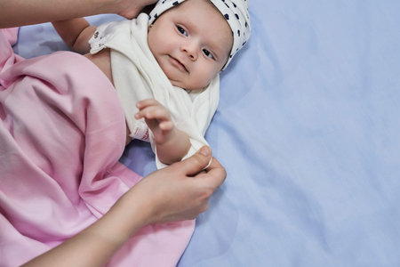 Young mother wears little baby girls headwear. Motherhood, sweet family, cute newborn baby girl. Little fashionable muslim baby girl wearing turbanの写真素材
