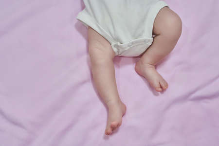Low Section Of Baby Feet Relaxing Over Blanket. Feet of the infant lying on pink backgraundの写真素材