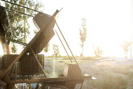 Close-Up Of Water Wheel By Promenade During Sunshining in villageの写真素材