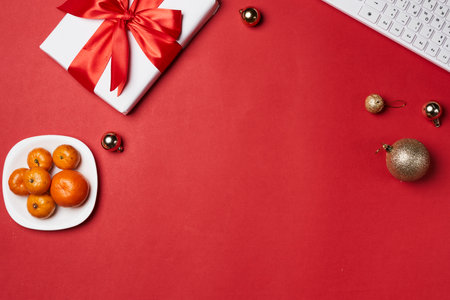 an office desk with a computer, keyboard and christmas ornaments on the table top view from above is a bowl of orangesの写真素材