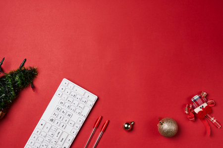a computer keyboard and christmas decorations on a red background with space for your own text or image to be addedの写真素材