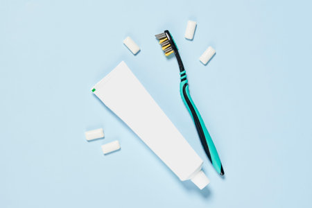 a toothbrush and some pieces of paper on a light blue background with copy space in the top right...