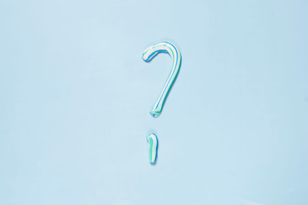 a persons hand holding a green and blue umbrella in the shape of a question mark on a white...