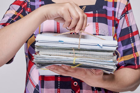 a woman holding a stack of papers and pulling it with her hands, while she is looking at the cameraの写真素材