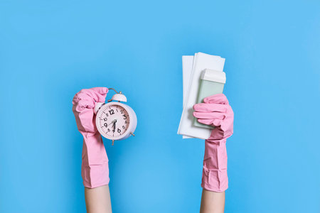 someones hands holding an alarm clock and gloved in pink rubber gloves on a blue background with...