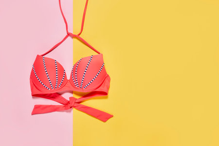 a bikini top on a yellow and pink background with copy - space in the bottom right handwritten text readsの写真素材