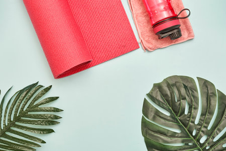 an exercise mat, towel and water bottle on a white background with palm leaves in the top view is from aboveの写真素材