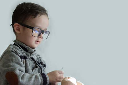 a young boy wearing glasses and playing with a remote control device in front of his face, against a...